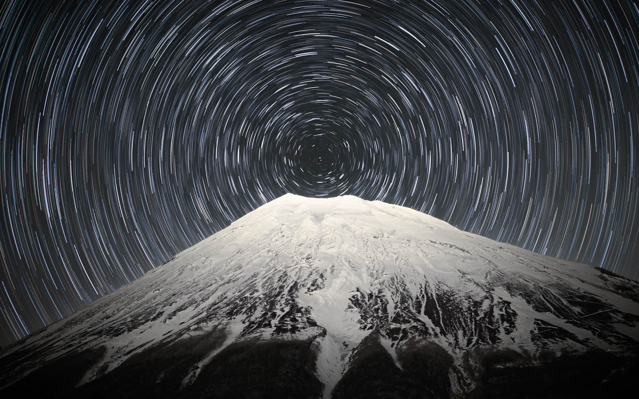 以北极星为中心、星轨环绕富士山顶的夜景合成图。