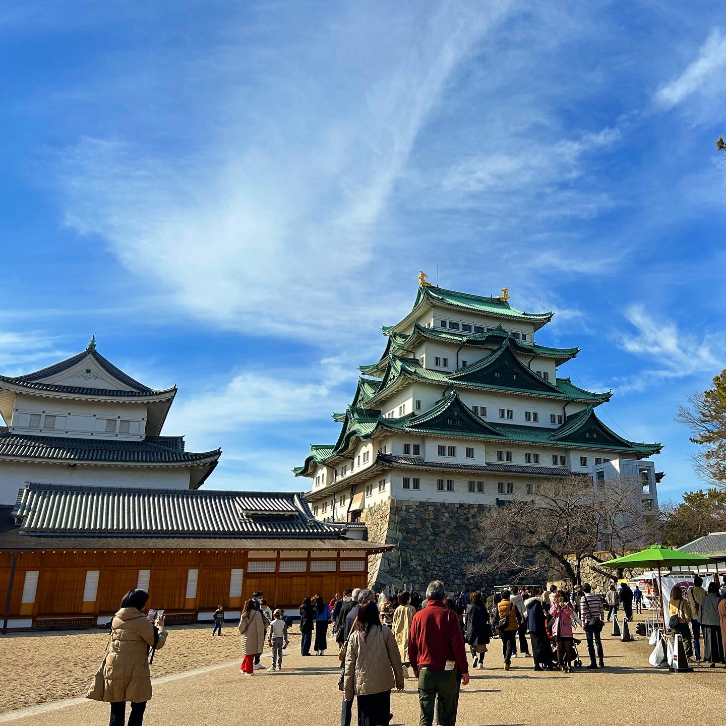 蓝天下名古屋城天守与前方游客。