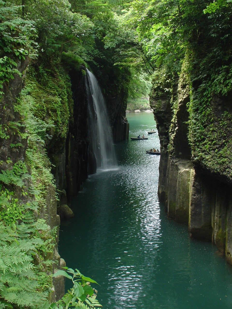 高千穗峡狭窄河道、垂直岩壁与划船游客。